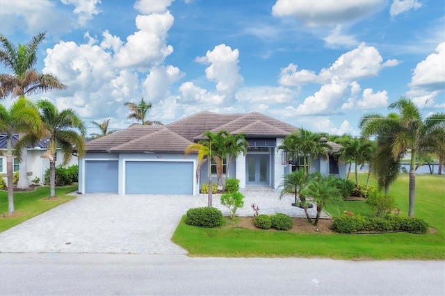 view of front facade with a garage, a front yard, and french doors