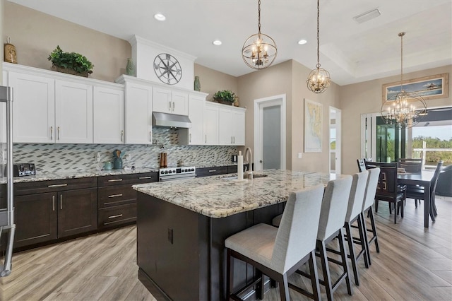 kitchen with an island with sink, tasteful backsplash, hanging light fixtures, and sink