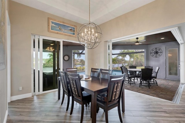 dining space featuring ceiling fan with notable chandelier and wood-type flooring