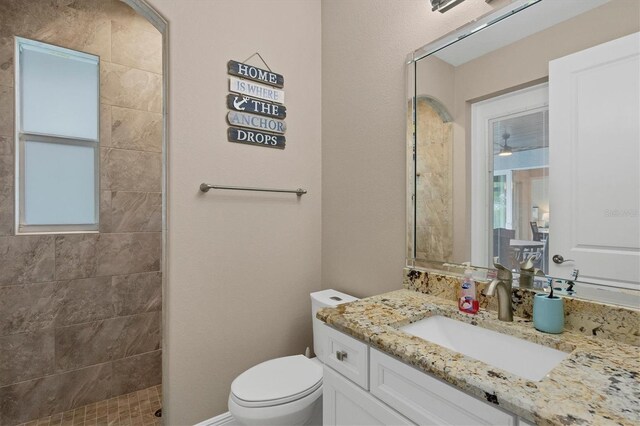 bathroom with toilet, vanity, and tiled shower