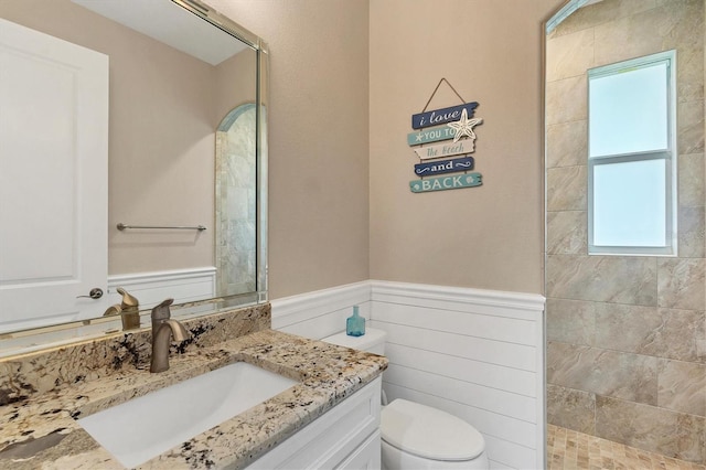 bathroom with a tile shower, vanity, and toilet