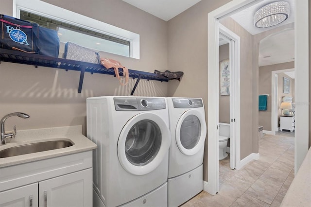 laundry room with cabinets, light tile patterned floors, sink, and washing machine and clothes dryer