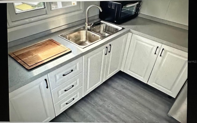 kitchen featuring dark hardwood / wood-style floors, white cabinetry, and sink