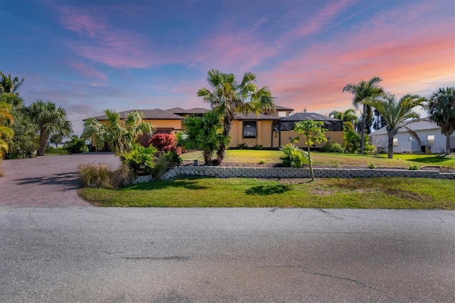 view of front of home with a lawn and a lanai