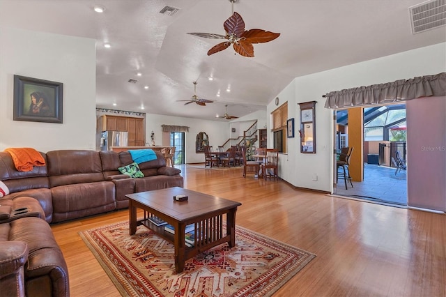 living room with ceiling fan, light hardwood / wood-style floors, and vaulted ceiling