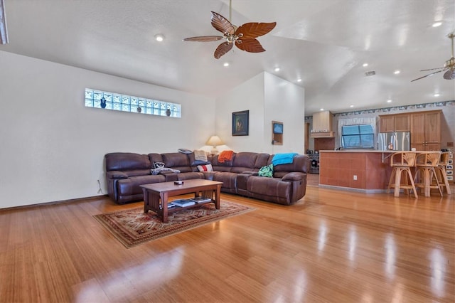 living room featuring light hardwood / wood-style floors, high vaulted ceiling, and ceiling fan