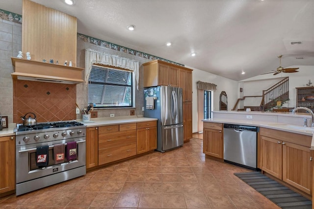 kitchen featuring lofted ceiling, sink, ceiling fan, appliances with stainless steel finishes, and kitchen peninsula