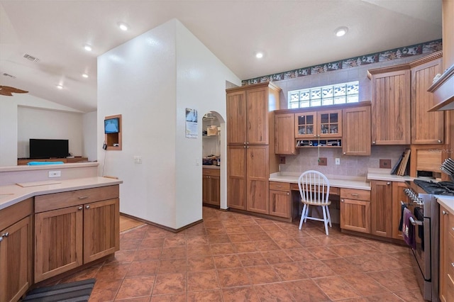 kitchen featuring decorative backsplash, high end range, built in desk, and lofted ceiling