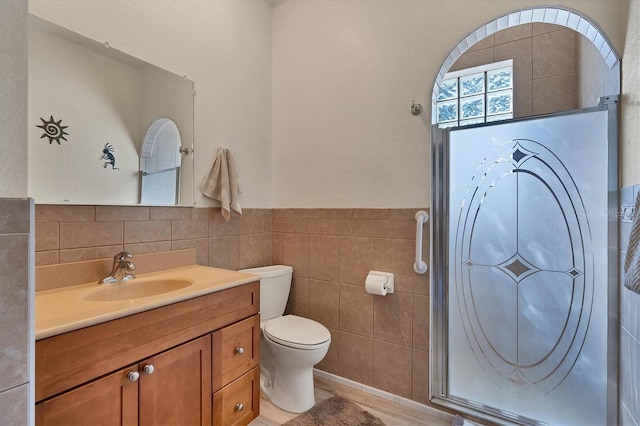 bathroom with wood-type flooring, vanity, toilet, and tile walls