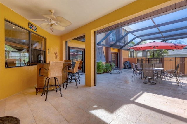 view of patio / terrace featuring ceiling fan, a lanai, and an outdoor bar