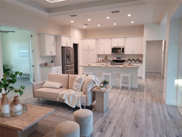 living room featuring light wood-style floors, recessed lighting, visible vents, and baseboards