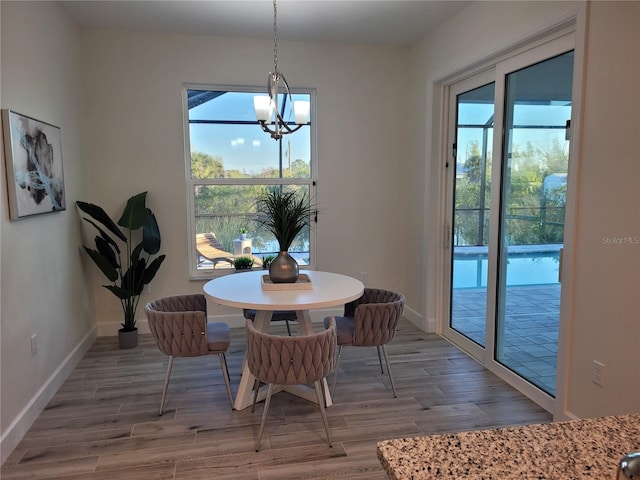 dining area with a notable chandelier, plenty of natural light, and wood finished floors