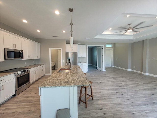 kitchen featuring recessed lighting, appliances with stainless steel finishes, light wood-style floors, white cabinets, and a sink