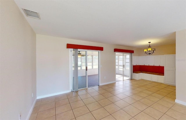 empty room with light tile patterned floors and an inviting chandelier