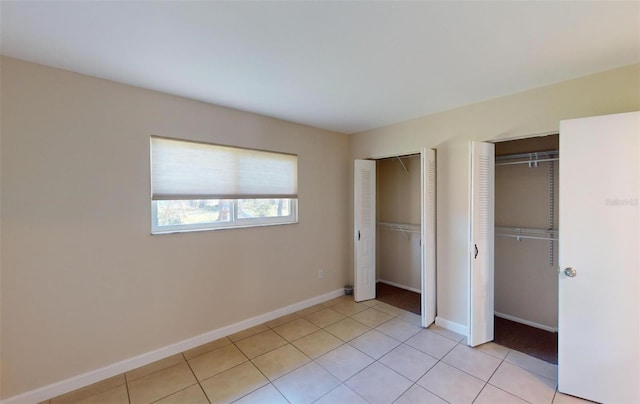 unfurnished bedroom featuring light tile patterned flooring and two closets