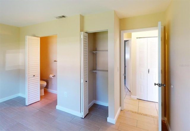 interior space featuring light wood-type flooring, connected bathroom, and a closet