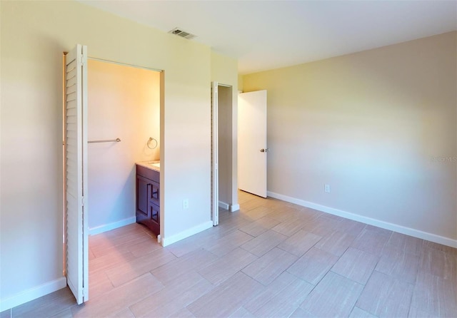 unfurnished bedroom with ensuite bathroom and light hardwood / wood-style floors