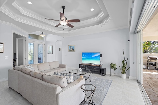 living room with a raised ceiling, a wealth of natural light, ornamental molding, and ceiling fan