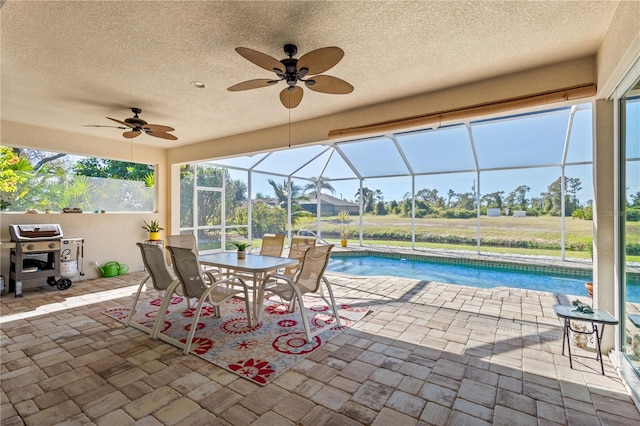 view of swimming pool with a lanai, ceiling fan, a patio area, and grilling area