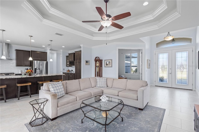 living room with french doors, a tray ceiling, ceiling fan, and ornamental molding