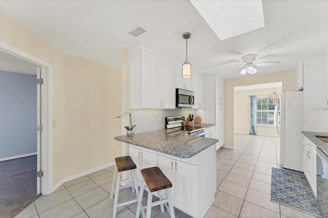 kitchen with stone counters, white cabinets, a breakfast bar area, kitchen peninsula, and stainless steel appliances