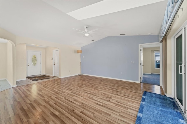 unfurnished living room featuring ceiling fan, light hardwood / wood-style floors, and lofted ceiling with skylight