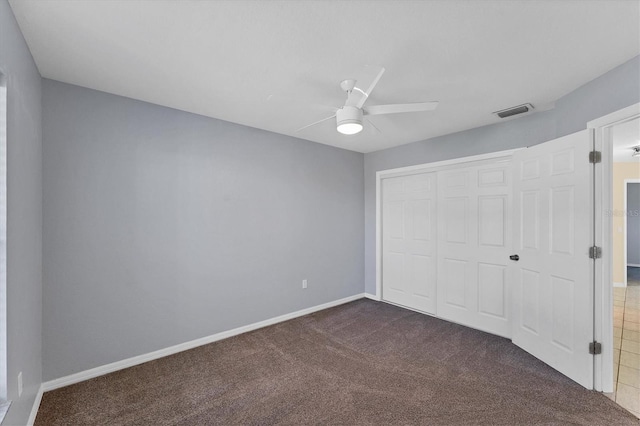 unfurnished bedroom featuring a closet, dark carpet, and ceiling fan