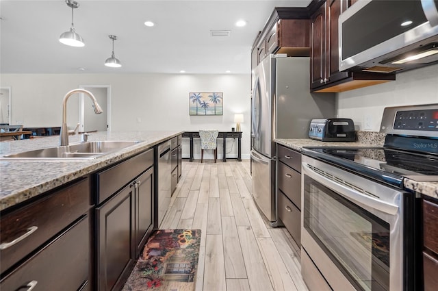 kitchen featuring dark brown cabinetry, sink, stainless steel appliances, light hardwood / wood-style flooring, and pendant lighting