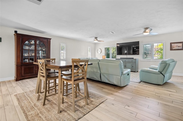 dining room with ceiling fan, light wood-type flooring, and a textured ceiling