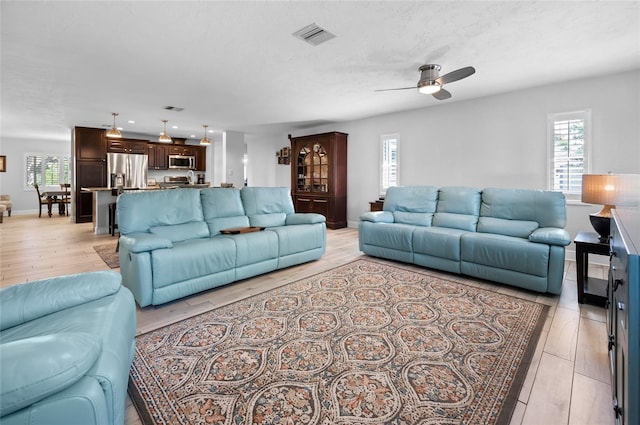 living room featuring a textured ceiling, light hardwood / wood-style floors, and ceiling fan