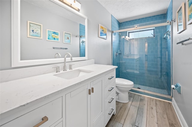 bathroom featuring toilet, vanity, a shower with door, and hardwood / wood-style flooring