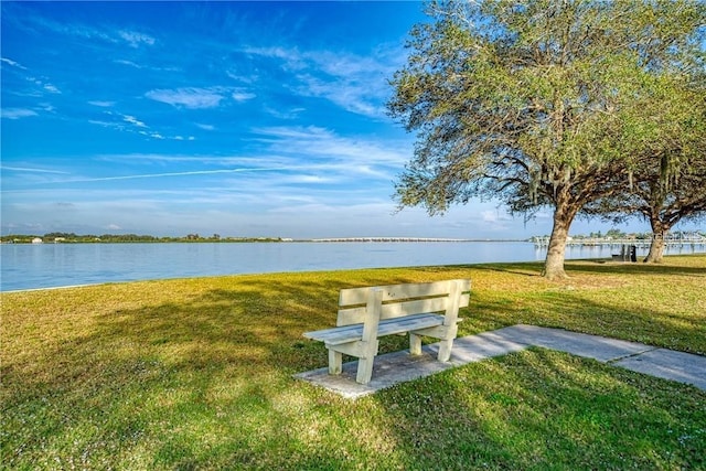 surrounding community with a water view and a lawn