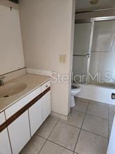 bathroom with a shower, vanity, tile patterned flooring, and toilet