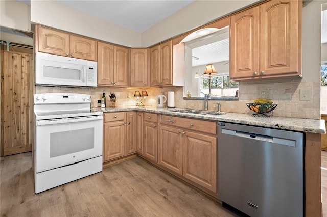 kitchen with light stone counters, sink, white appliances, and light hardwood / wood-style floors