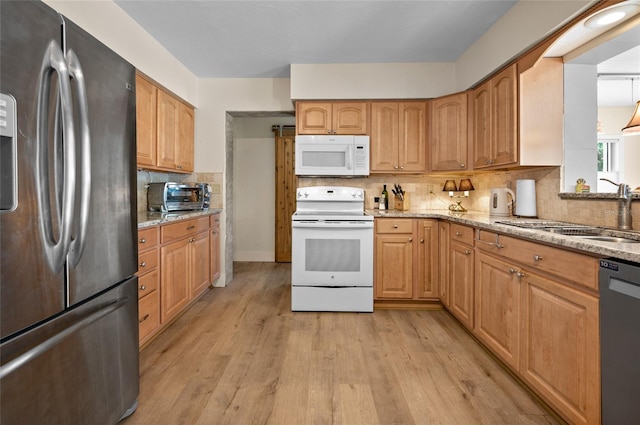 kitchen featuring sink, white appliances, light hardwood / wood-style flooring, backsplash, and light stone countertops