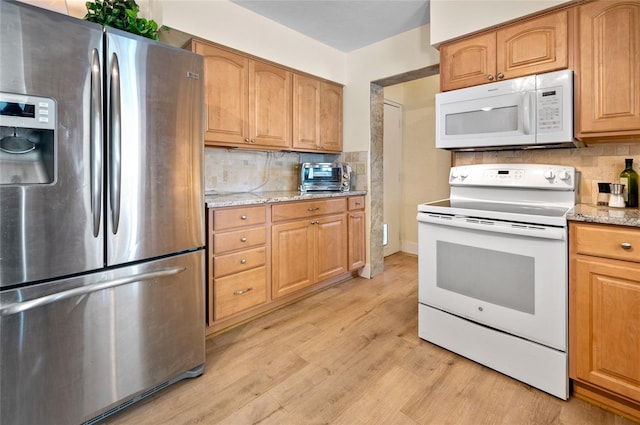 kitchen featuring tasteful backsplash, light stone counters, white appliances, and light hardwood / wood-style flooring