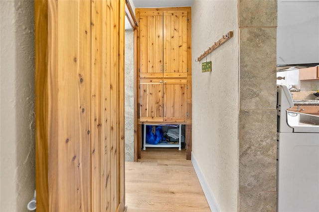 corridor with washer / dryer and light wood-type flooring