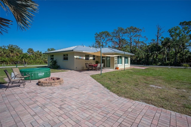 rear view of property with a patio, a lawn, and a fire pit