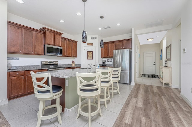 kitchen featuring a kitchen breakfast bar, a kitchen island with sink, light hardwood / wood-style flooring, and stainless steel appliances