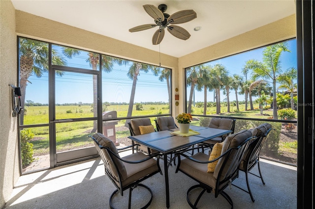 sunroom / solarium with a wealth of natural light, ceiling fan, and a rural view