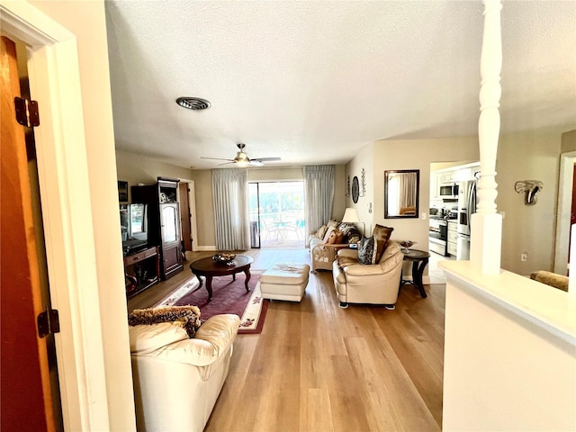 living room with ceiling fan, light hardwood / wood-style floors, and a textured ceiling