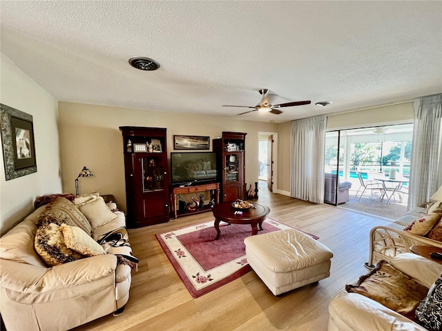 living room featuring ceiling fan, a textured ceiling, and light hardwood / wood-style flooring