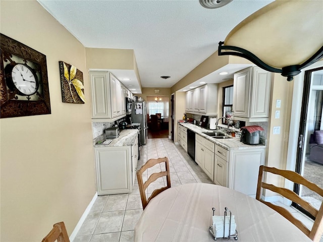 kitchen featuring sink, stainless steel fridge, light tile patterned floors, black dishwasher, and light stone counters