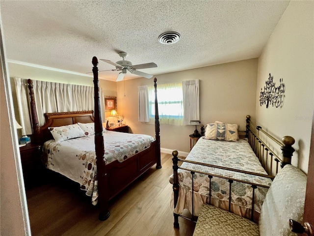 bedroom featuring ceiling fan, light hardwood / wood-style flooring, and a textured ceiling