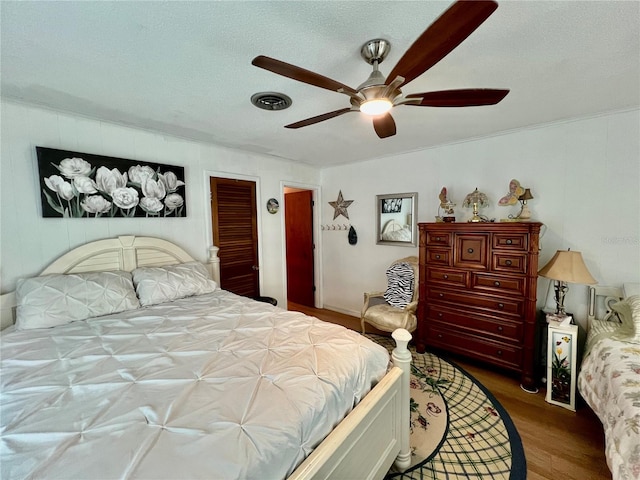 bedroom with ceiling fan, dark wood-type flooring, and a textured ceiling