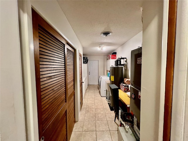 hall featuring light tile patterned floors, a textured ceiling, and washer and clothes dryer