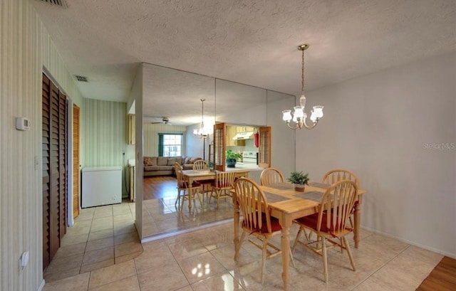 dining area featuring ceiling fan with notable chandelier, a textured ceiling, and light wood-type flooring