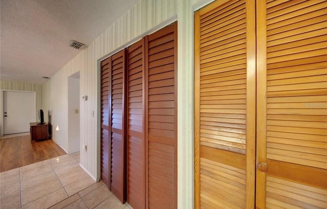 hallway with light tile patterned floors and a textured ceiling