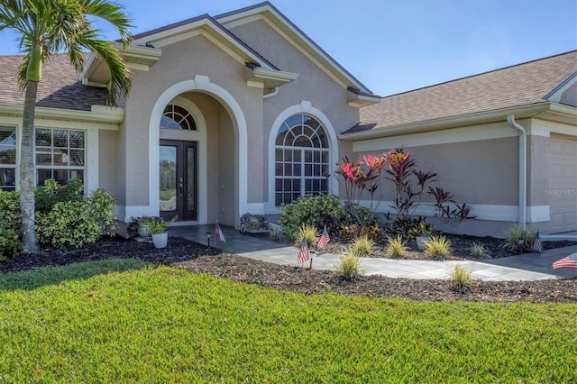 view of exterior entry featuring a garage and a yard