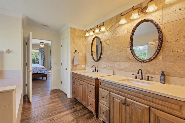 bathroom with vanity, hardwood / wood-style flooring, ceiling fan, ornamental molding, and tile walls